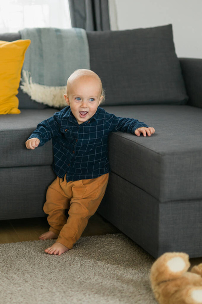 Caucasian baby newborn infant making first steps. Cute toddler kid child son boy learning walking creeping on living room. Childcare and childhood - Fotografie, Obrázek