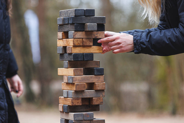 Jenga tower game in nature. Close-up shot of Jenga wooden block game. Concept of risk management. High quality photo - Zdjęcie, obraz