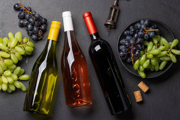 Masada şarap şişeleri, üzümler, tirbuşon ve şarap mantarları var. Mesaj için bolca yer var. Düz yatıyordu - Fotoğraf, Görsel