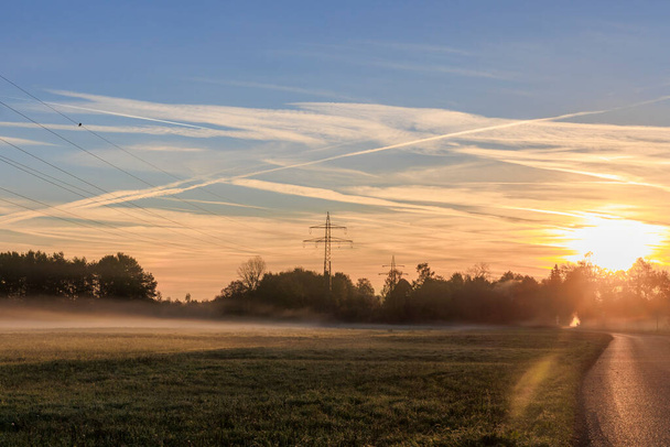 colorful sunrise over foggy meadows at a dirt road in Augsburg city forest near Siebenbrunn - Photo, Image