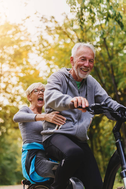 Vrolijk actief seniorenpaar samen op de fiets. Perfecte activiteiten voor ouderen. - Foto, afbeelding
