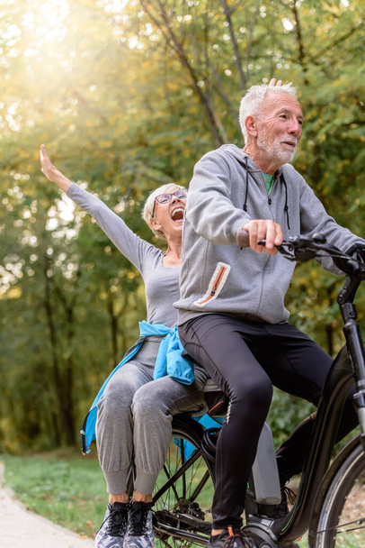 Χαρούμενο ενεργό ζευγάρι ηλικιωμένων με ποδήλατο μαζί. Ιδανικές δραστηριότητες για ηλικιωμένους. - Φωτογραφία, εικόνα
