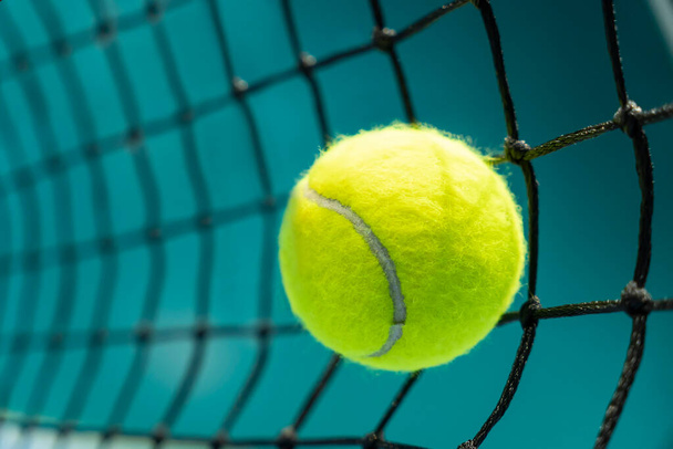 μια μπάλα του τένις χτύπησε ένα μαύρο δίχτυ στο παρασκήνιο ενός γηπέδου τένις - Φωτογραφία, εικόνα
