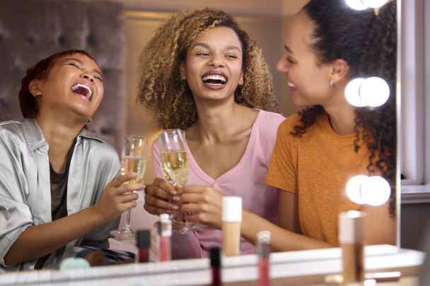 Group Of Female Friends At Home Putting On Make Up And Drinking Champagne Before Night Out - Foto, immagini