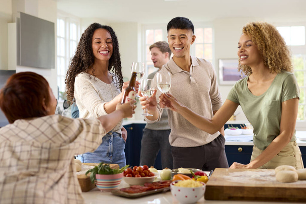 Group Of Friends At Home In Kitchen With Drinks Making Food For Party - Photo, Image