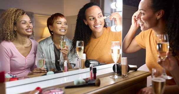 Group Of Female Friends At Home Putting On Make Up And Drinking Champagne Before Night Out - Foto, Imagem