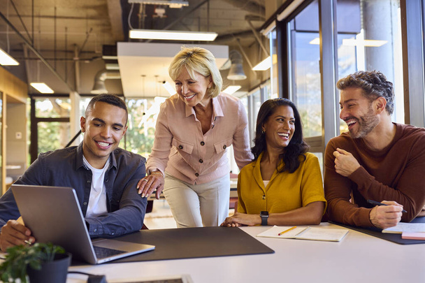 Multi-Cultural Business Team Meeting Around Laptop In Modern Office - Foto, afbeelding