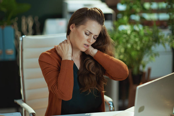 stressed stylish small business owner woman with neck pain in the modern green office. - Foto, imagen