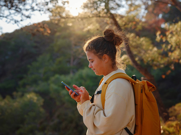 Travel and active lifestyle concept. Happy smiling woman hiking in mountains , Fethie, Turkey. Young Hiker using smart phone, Digital communication. Texting with friends in social network, outdoors - Photo, Image