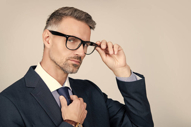mature entrepreneur in businesslike suit and glasses on grey background. copy space. - Fotó, kép