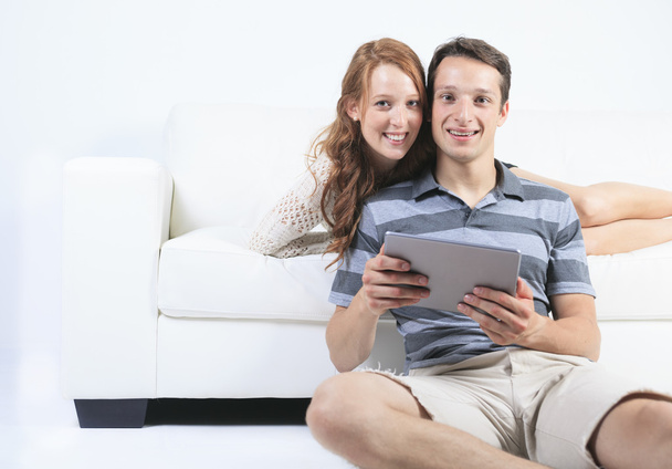 Una hermosa pareja en el sofá con tableta digital
 - Foto, imagen