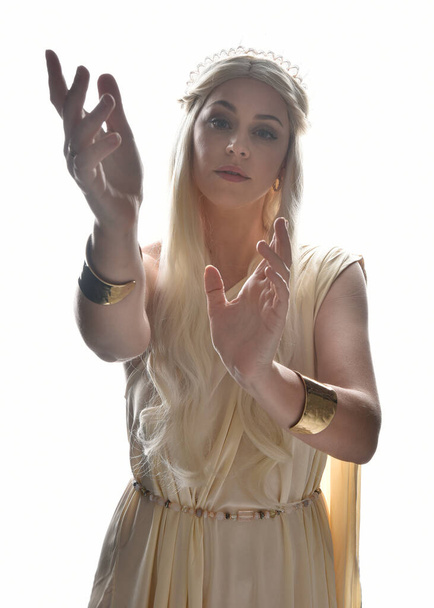 Close up portret pięknej blondynki model, noszenie bogini fantasy toga sukienka z kryształową koronę tiara. Podświetlić świecące odizolowane tło studio z oświetleniem sylwetki. - Zdjęcie, obraz