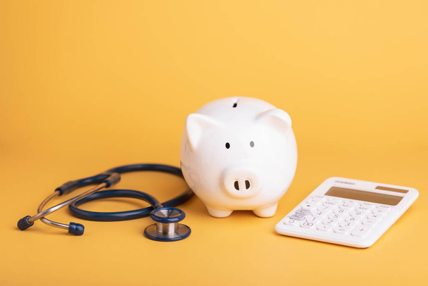 Financial health check, The idea of taking care of saving money, Man using stethoscope to check white piggy bank on desk with grey copy space background. Health and finance concept - Foto, Bild