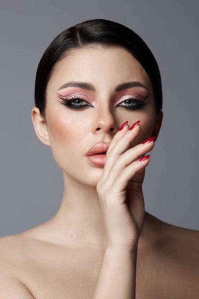 Beauty portrait of a woman, pink eye shadow makeup, arrows and long eyelashes. Brunette woman, red nail polish, natural cosmetics - Fotoğraf, Görsel