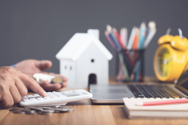 House purchase and cost idea, Home interest calculate concept. Man using calculator on office desk to plan and find the number of money for house financial. Residence buying planning. Studio shot. - Φωτογραφία, εικόνα