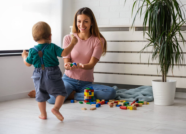 mother playing with son, using wooden cubes - Photo, Image