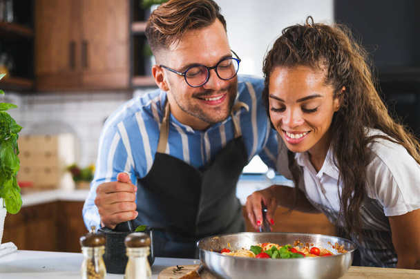 beautiful young couple in love in the kitchen cooking together - Фото, изображение