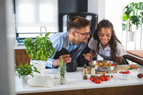 όμορφο νεαρό ζευγάρι ερωτευμένο στην κουζίνα να μαγειρεύουν μαζί - Φωτογραφία, εικόνα
