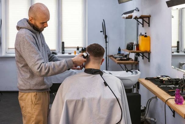 Ein Friseur oder Friseur arbeitet mit einer Rasiermaschine am Haar. - Foto, Bild