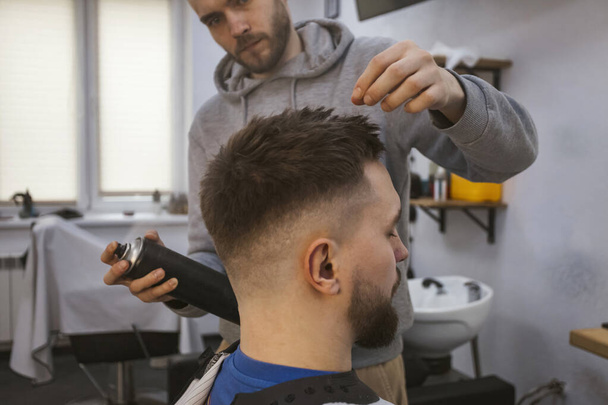Le coiffeur ou le coiffeur applique des touches de finition et de style sur les cheveux. - Photo, image