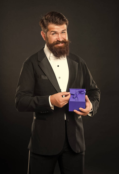 happy man in tuxedo bow tie formalwear on black background with business reward box. occasion greeting. - Фото, зображення