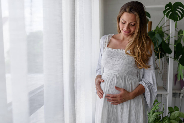 junge schwangere Frau posiert am Fenster - Foto, Bild