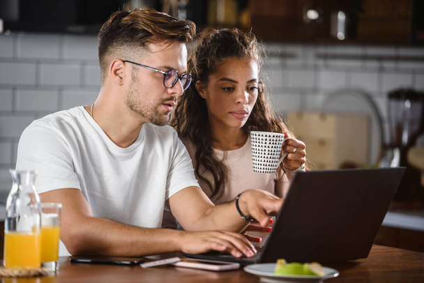 uomo e donna guardando qualcosa sul computer portatile mentre stanno facendo colazione - Foto, immagini