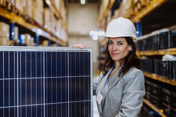 Portrait du manager tenant un panneau solaire dans un entrepôt. - Photo, image