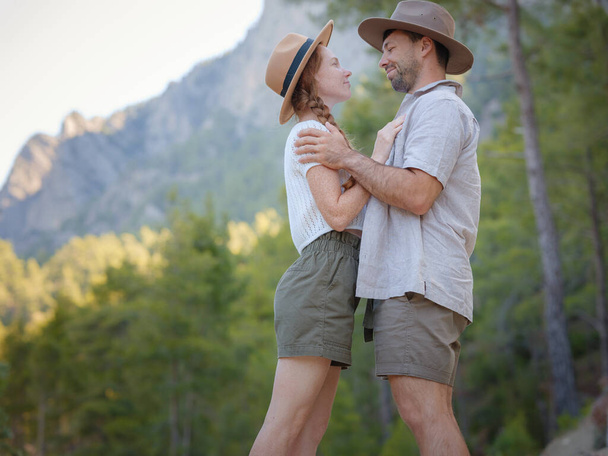 concept of embracing fresh air and engaging in outdoor activities. Loving young couple hugging and smiling together on nature background. Mountains Forest walk in Turkey - Photo, image