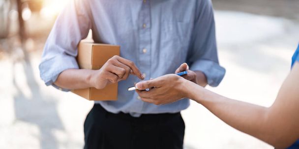 customer signature in mobile phone, man receiving parcel box from courier with delivery service man, express delivery, online shopping concept. - Foto, imagen