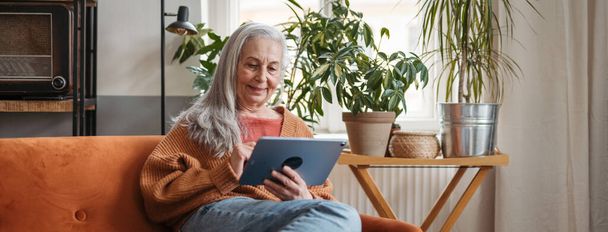 Mulher sênior gastando seu tempo livre com um tablet digital. - Foto, Imagem