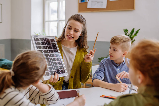 Young teacher with solar panel learning her pupils about solar energy. - Foto, imagen