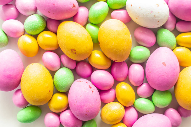 Colored dragees and chocolate eggs. Easter sweets closeup background - Photo, Image