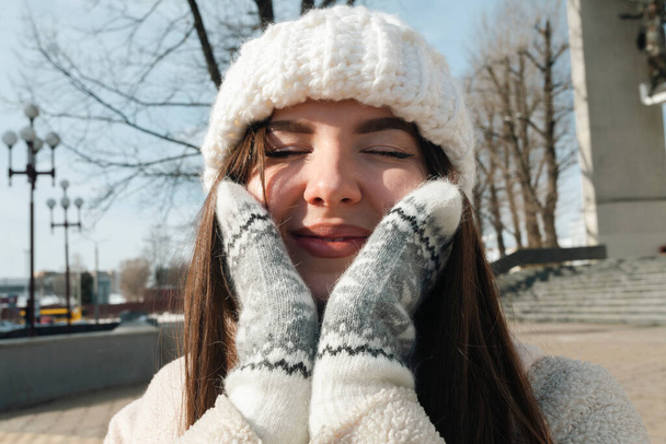 Sokak fotoğrafı. Güneşli bir kış gününde kısmen karlı caddelerde yürüyen çekici bir esmer kadın.. - Fotoğraf, Görsel