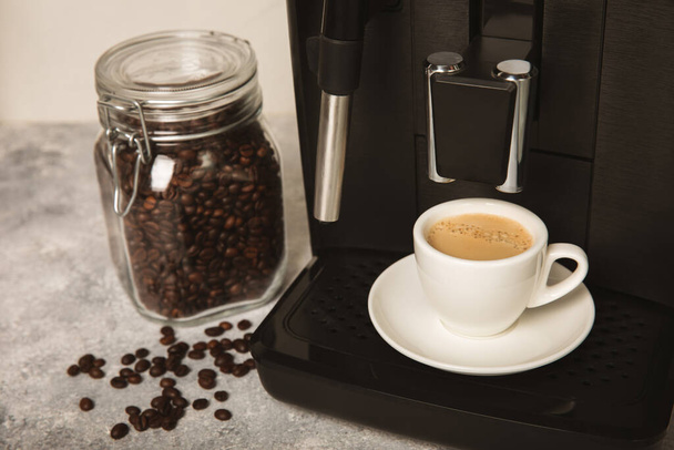 Modern coffee machine with cup in kitchen closeup interior. Cup of hot strong fragrant espresso. Morning coffee. Espresso machine on a wooden table. space for text. copy space. - Photo, Image