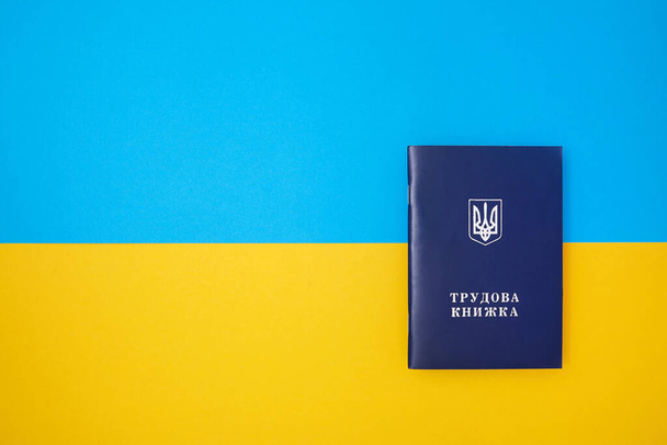 One blue Ukrainian work book on the Ukrainian national flag in the top view - Photo, Image