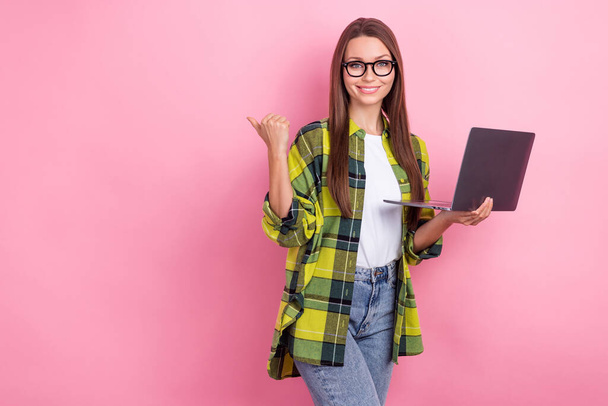 Photo of good mood nice woman with long hairstyle checkered shirt indicating empty space hold laptop isolated on pink color background. - Valokuva, kuva