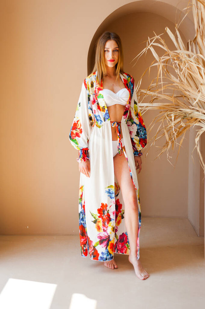 красива молода жінка в літній сукні позує на білому тлі
 - Фото, зображення