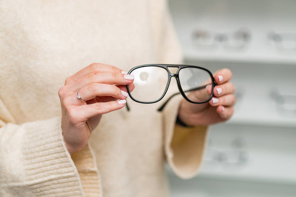 Eyewear accessory in woman hands. Modern eyeglasses holding by hands. - Фото, зображення