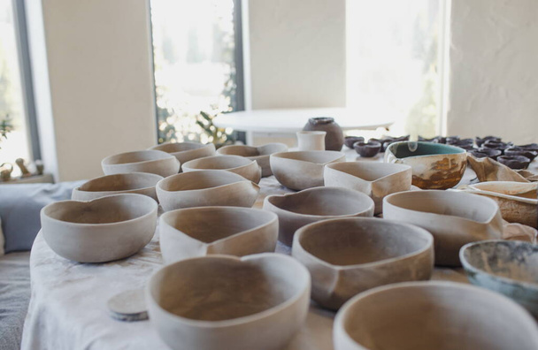 A lot of unpainted pottery is on a wooden table. - Foto, Bild