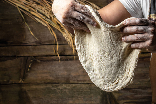 Змішуючи тісто, руки роблять тісто для піци або хліба
. - Фото, зображення