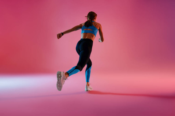 Жінка бігає під час кардіо-тренувань на фоні студії. Високоякісна фотографія
 - Фото, зображення