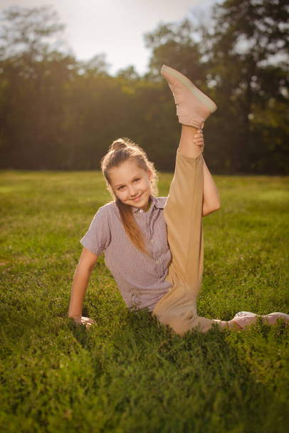 sorrindo ginasta adolescente faz ginástica ao ar livre e grava vídeo de treinamento. menina dançarina no parque verde no dia ensolarado - Foto, Imagem