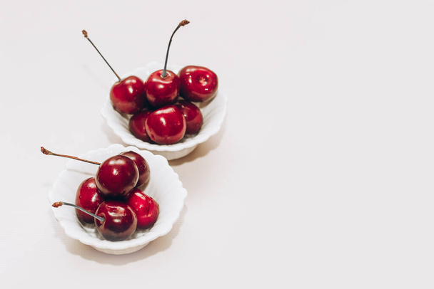Cerejas vermelhas maduras em pratos brancos na mesa. - Foto, Imagem
