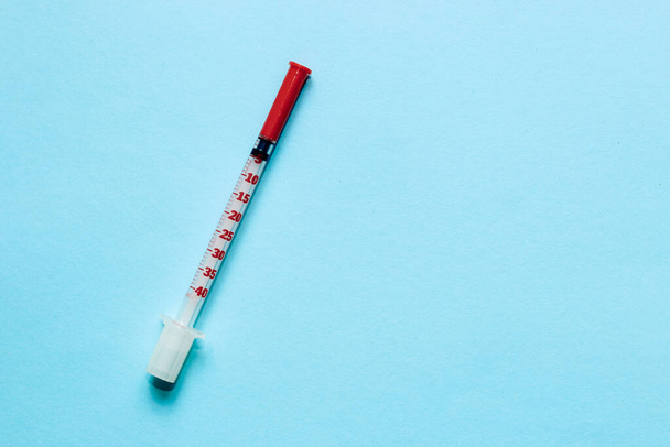 Thin insulin syringe on a blue background. - Foto, imagen