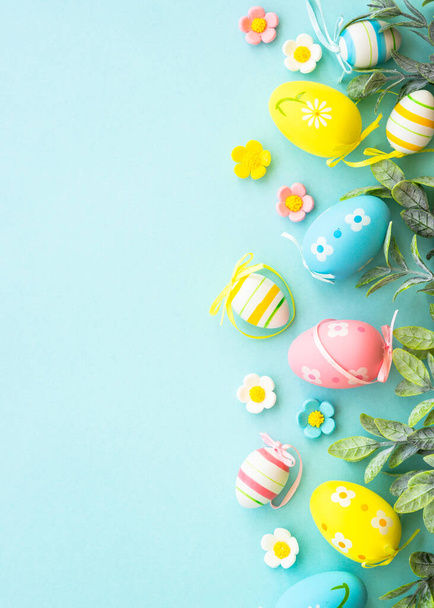 Fondo de Pascua o tarjeta de felicitación en azul. Huevos, hojas de primavera, flores y mariposas de colores. Vertical con espacio de copia - Foto, imagen