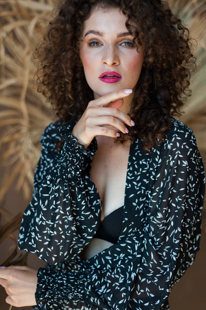beautiful young woman with curly hair and red lips posing in the city - Фото, изображение