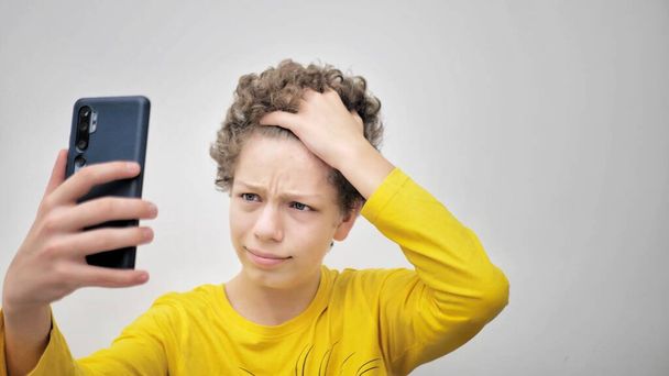 teenager squeezes pimples while looking at phone. The problem of teenage acne - Foto, Imagem