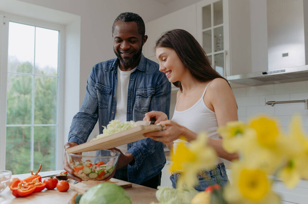 Gros plan d'une planche à découper avec les mains d'un couple coupant des légumes ensemble dans la cuisine. Aliments végétariens sains - Photo, image
