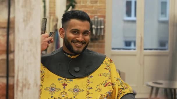 Улыбающийся индиец смотрит на зеркало в то время как парикмахер с помощью бритвы, чтобы аккуратно. Высококачественные 4k кадры - Кадры, видео
